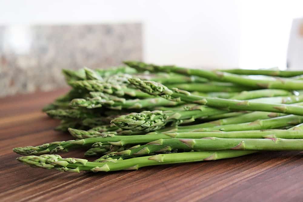 a bunch of asparagus on a wood cutting board