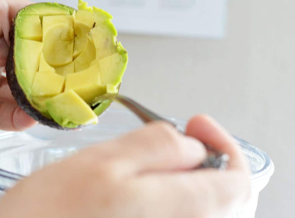 Scooping diced avocado into blender