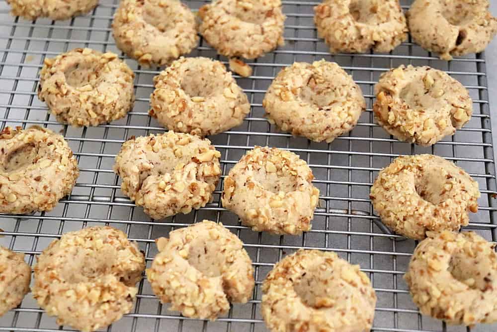Baked thumbprint cookies on a cooling rack ready for filling