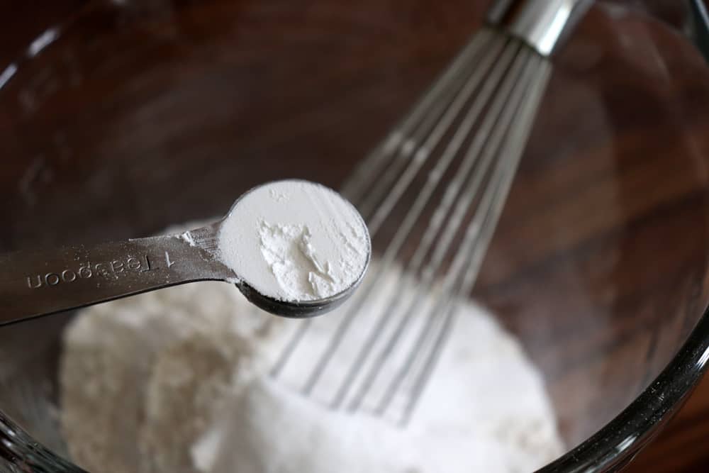 Adding baking powder to a glass bowl with a whisk