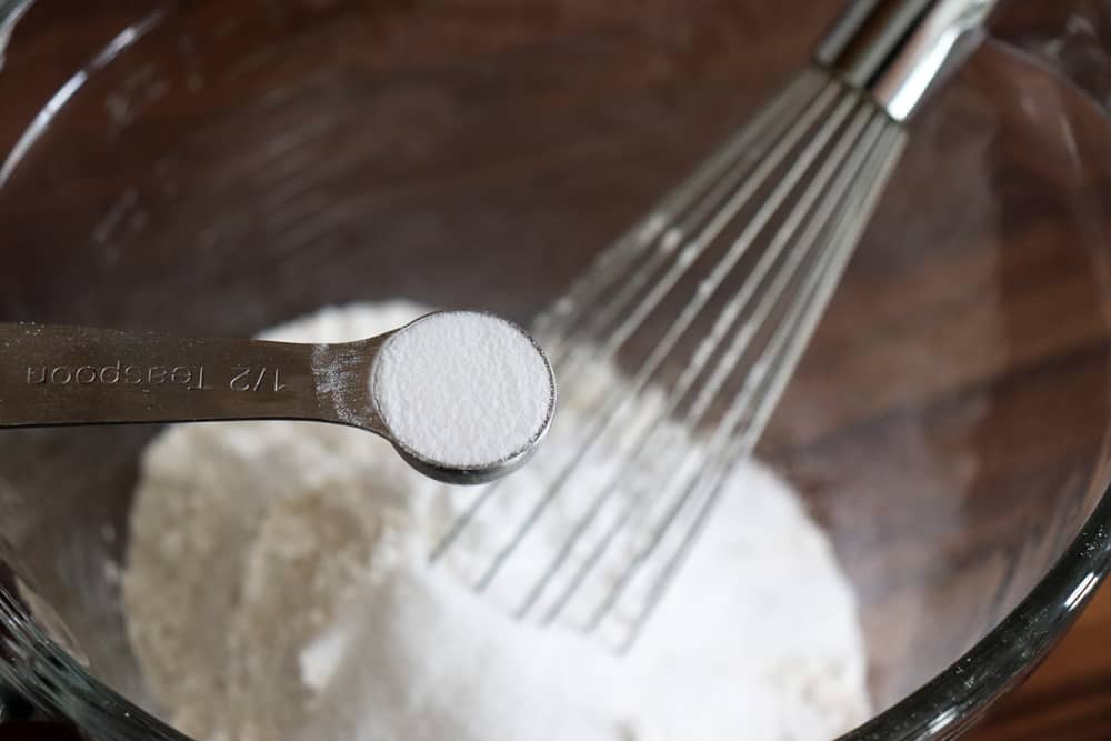 Adding baking soda to a glass bowl with a whisk
