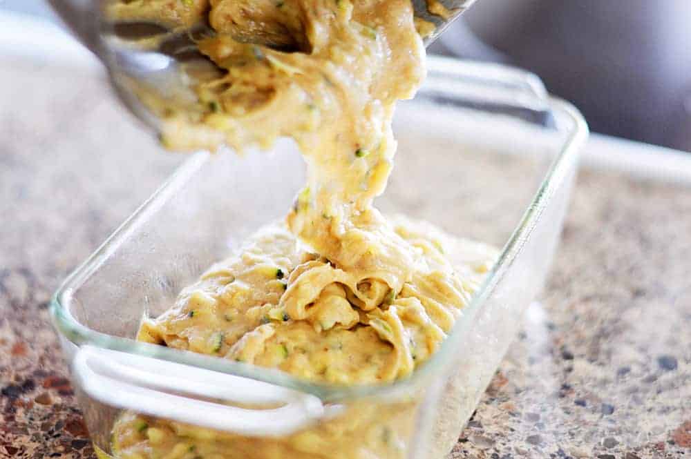 Pouring batter into a glass loaf pan for Zucchini Bread Recipe