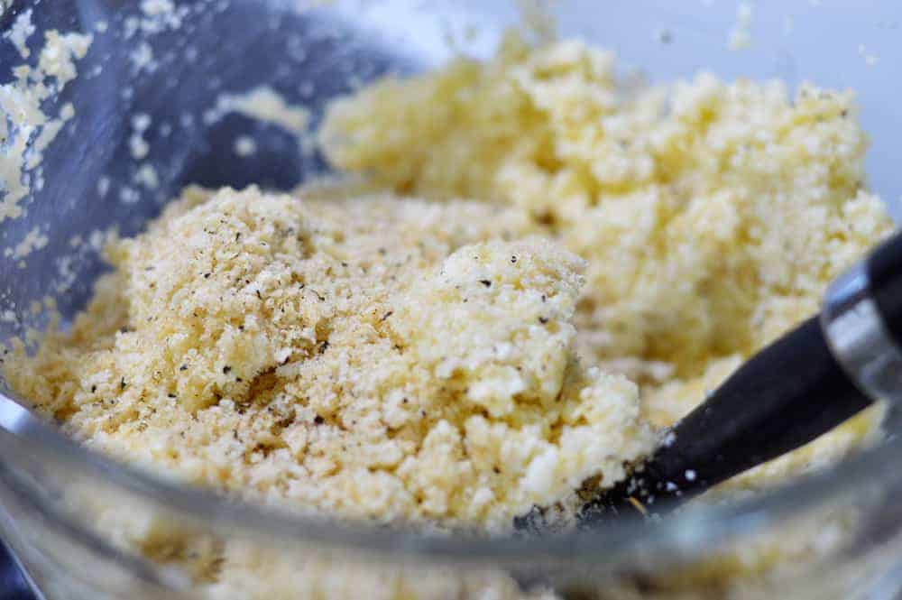 Adding breadcrumbs to ingredients in a glass bowl