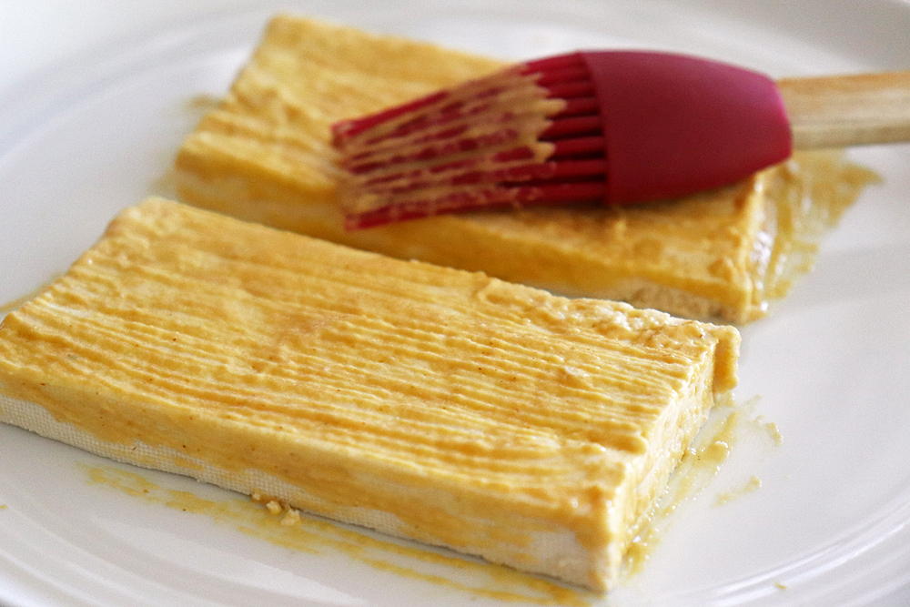 Brushing mustard on tofu steaks