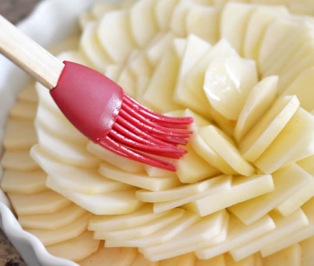 Brushing the potato slices with melted butter