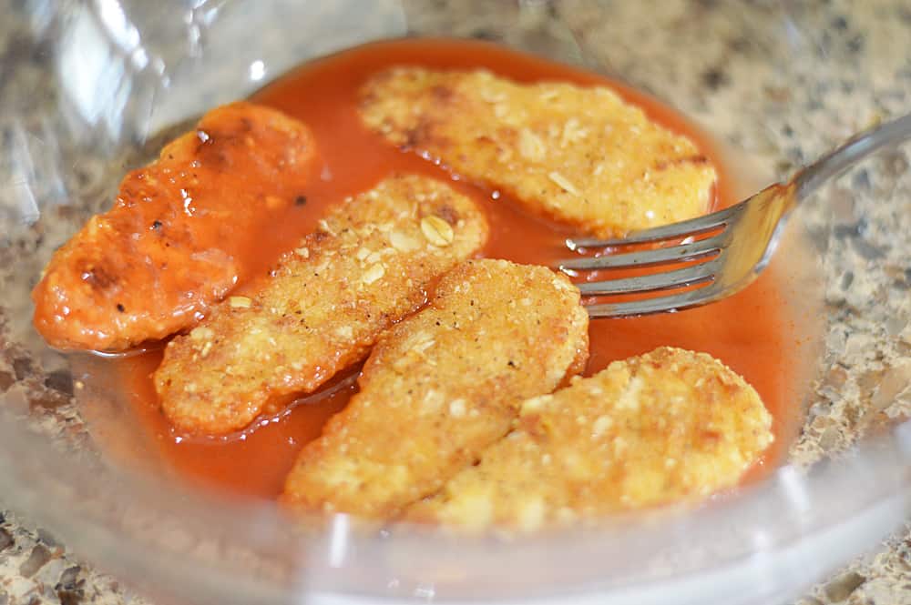 Coating Crispy Tenders in Buffalo Sauce for Vegan Buffalo Crispy Tender Roll Ups