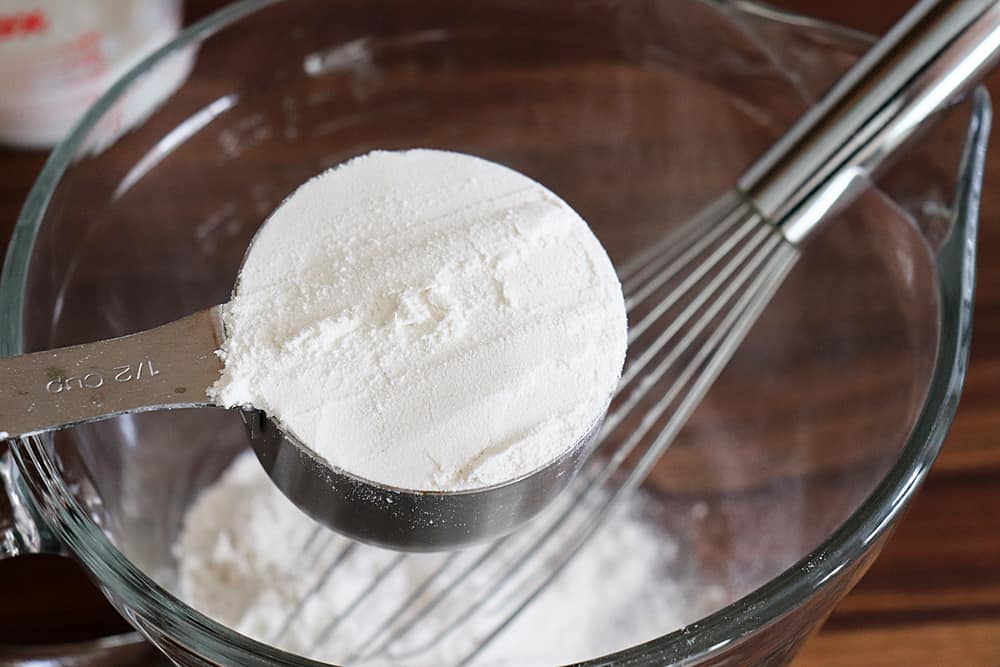 Adding flour to a glass bowl with a whisk