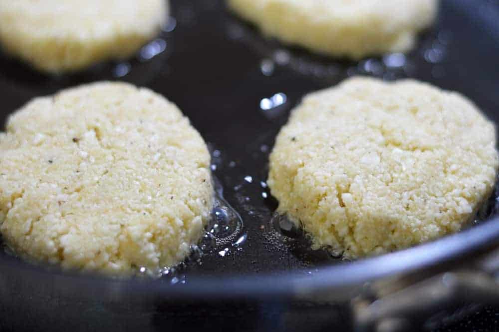 Cauliflower Fritters formed and frying in a pan