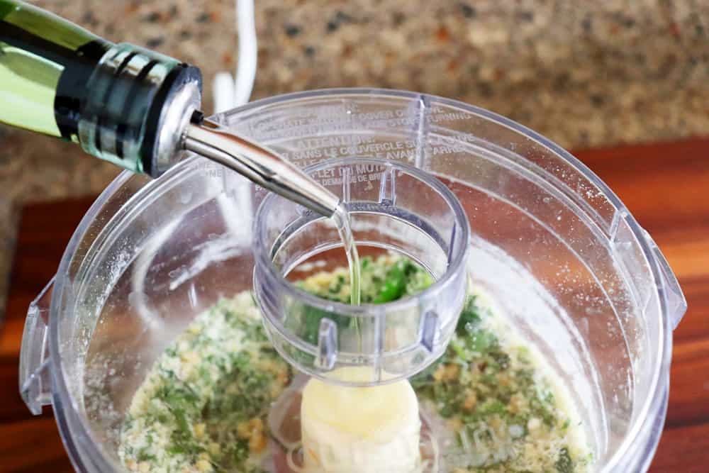 Adding oil to the food processor for Crispy Smashed Potatoes with Parsley Pesto