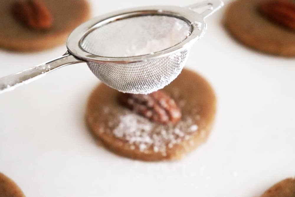 Dusting the unbaked pecan sandie with powdered sugar
