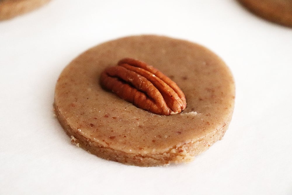 Placing a pecan half onto the unbaked cookie