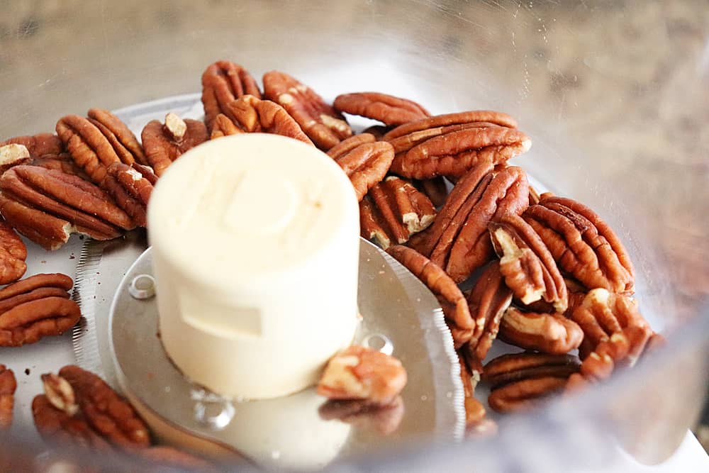 Roasted and cooled pecans in food processor
