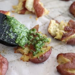 Brushing pesto on Crispy Smashed Potatoes with Parsley Pesto