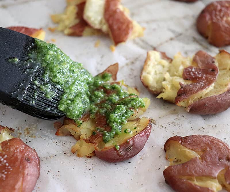 Brushing pesto on Crispy Smashed Potatoes with Parsley Pesto