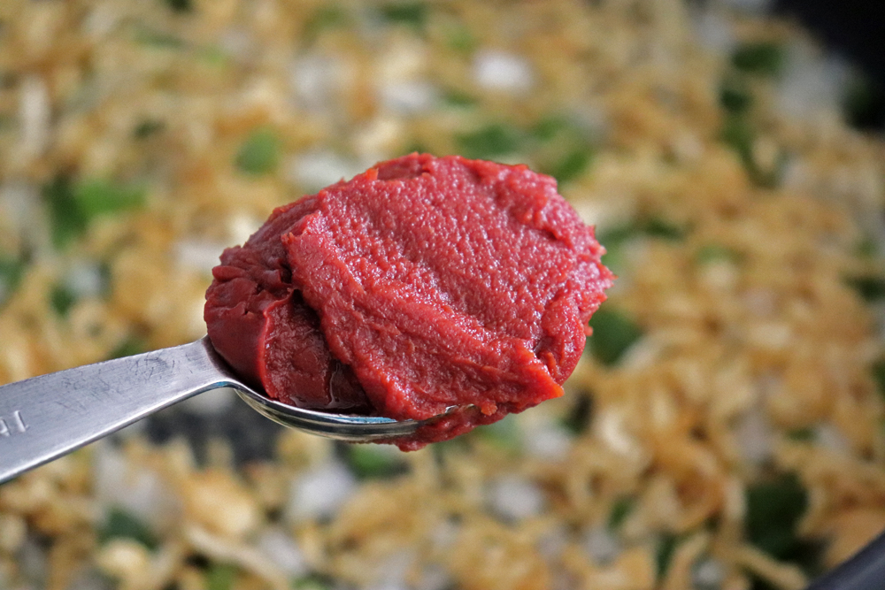Adding tomato paste to the fried tofu