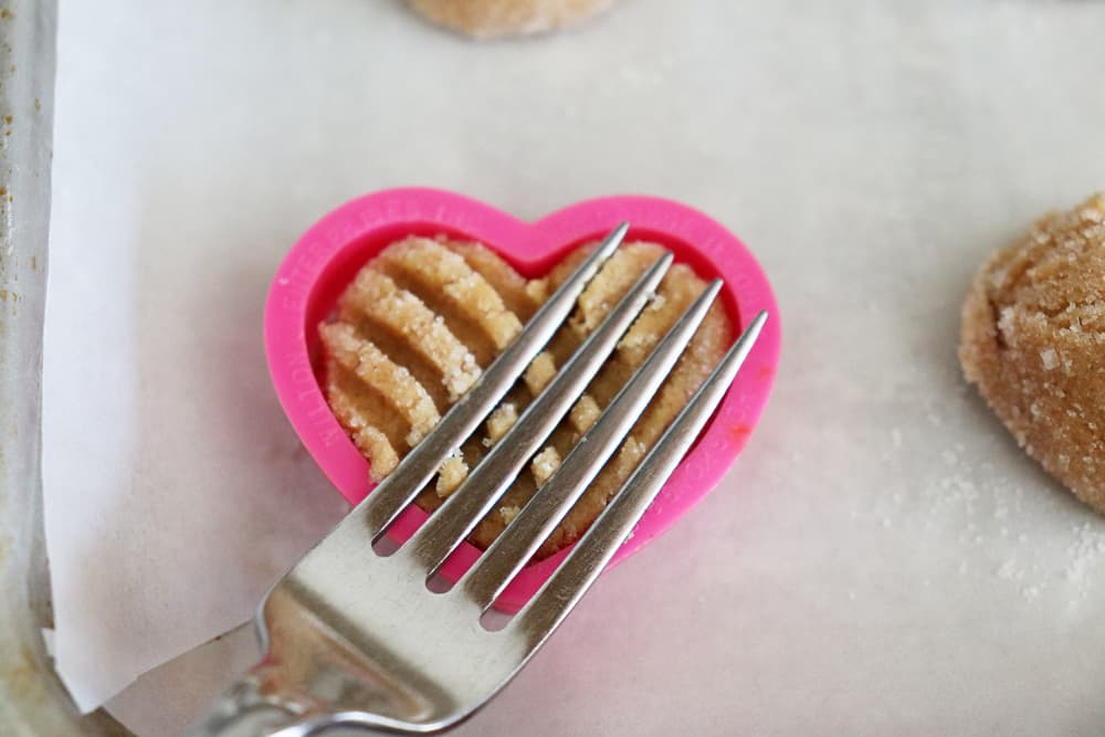 Using a fork and small pink cookie cutter to form the Vegan Peanut Butter Cookies