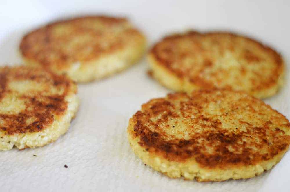 Draining cauliflower fritters on paper towels to remove excess oil