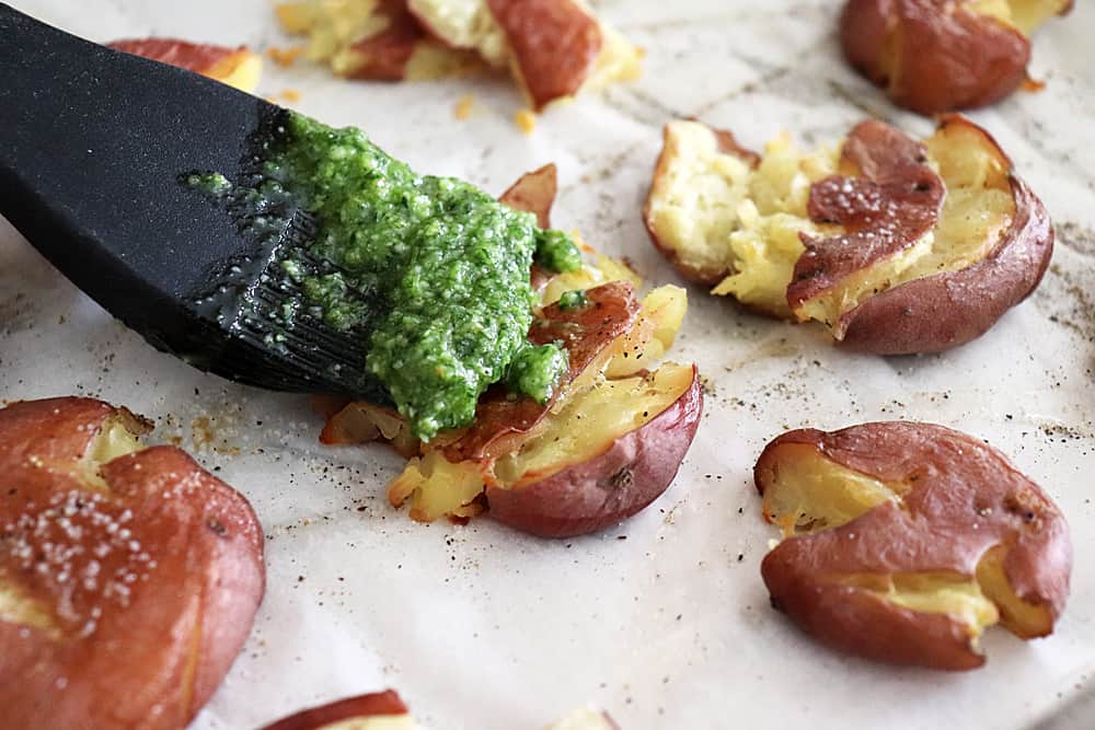 Brushing pesto on potatoes before serving